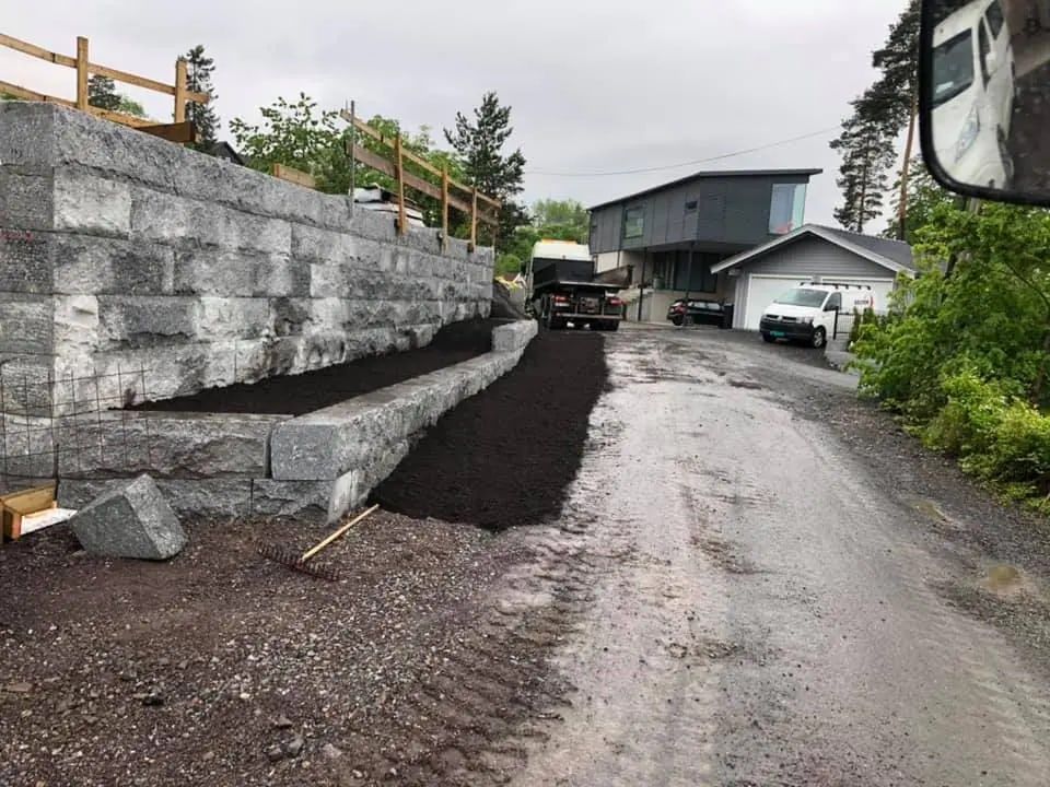 Opparbeidet tomt med støttemur i betongblokker, ny jord og grusvei